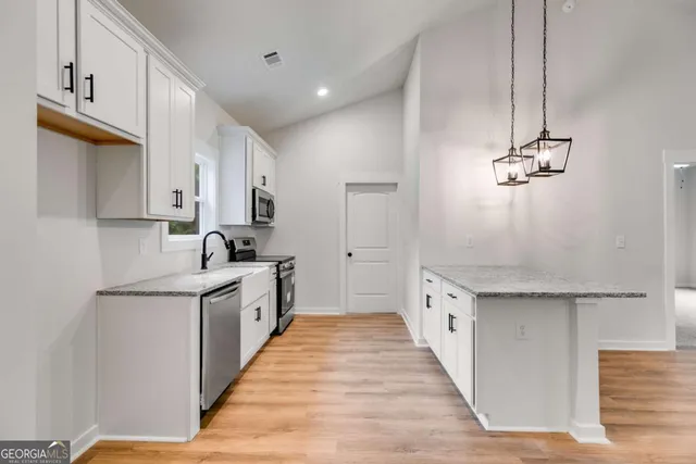 a large kitchen with stainless steel appliances granite countertop a sink and a refrigerator