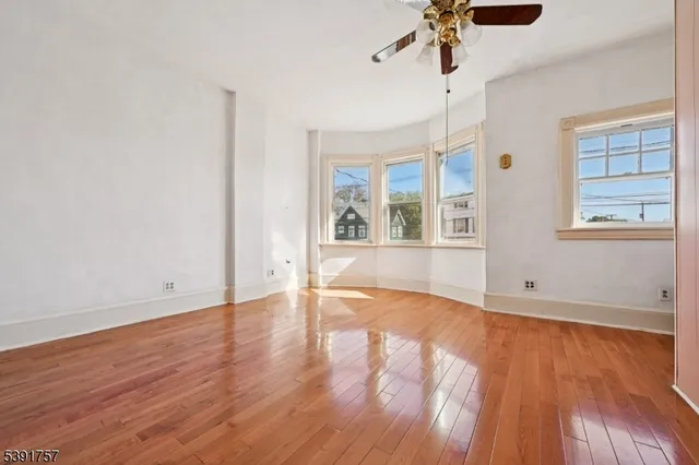 an empty room with wooden floor chandelier and windows