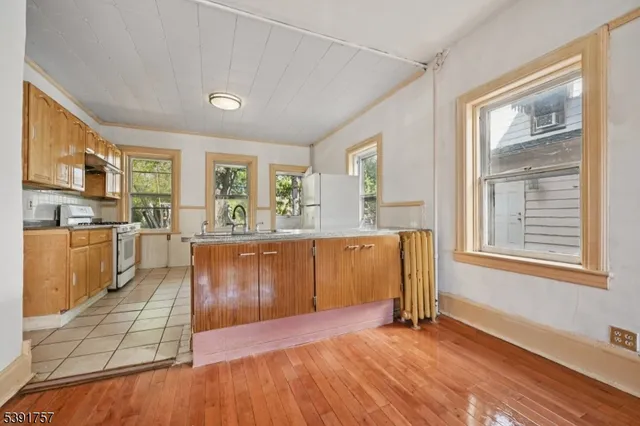 a living room with stainless steel appliances granite countertop a refrigerator a sink a stove with wooden floors and cabinets