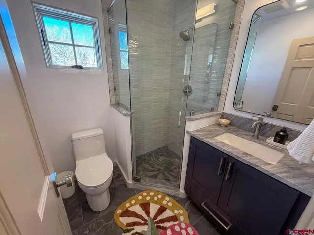 a bathroom with a granite countertop toilet sink and mirror
