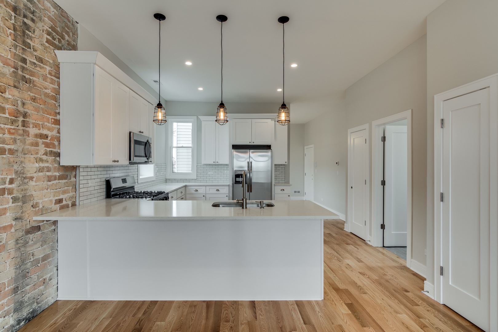 965 West 18th Street Chicago, IL 60608 - Photo 23 of 46 a large kitchen with stainless steel appliances a large counter top a sink a refrigerator and a window