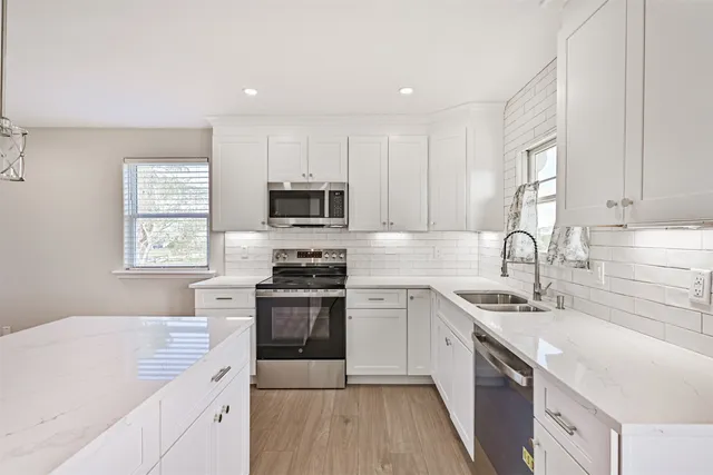 a kitchen with a sink cabinets appliances and a window