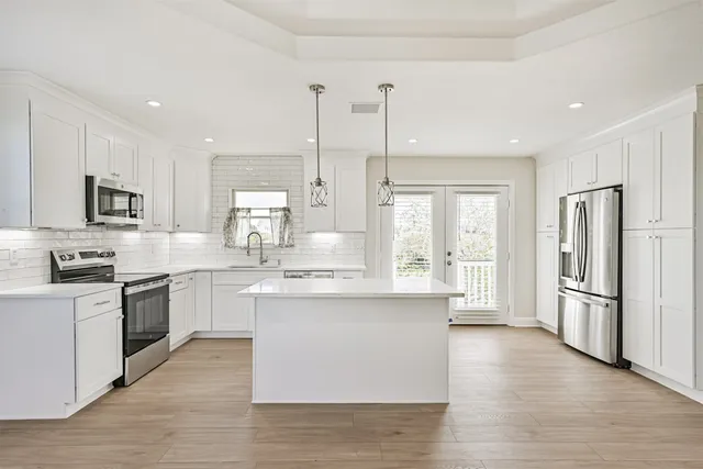 a large kitchen with stainless steel appliances kitchen island granite countertop a stove top oven a refrigerator a sink and dishwasher with wooden floor