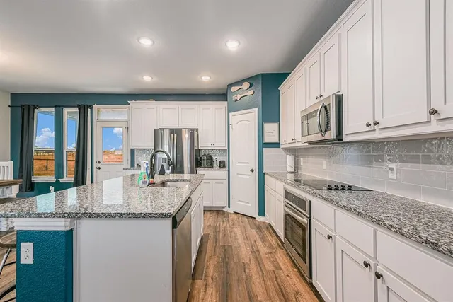 a kitchen with granite countertop stainless steel appliances sink stove microwave and cabinets