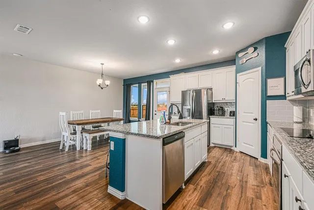 a kitchen with stainless steel appliances kitchen island granite countertop a stove refrigerator and cabinets