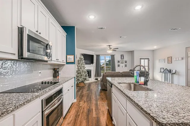 a kitchen with stainless steel appliances granite countertop a lot of counter space and wooden floors
