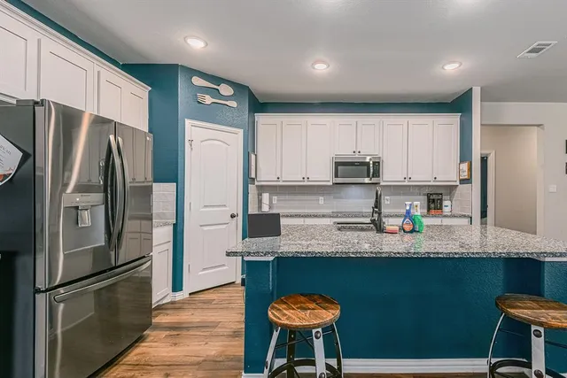 a kitchen with stainless steel appliances granite countertop a refrigerator a stove a sink and a microwave