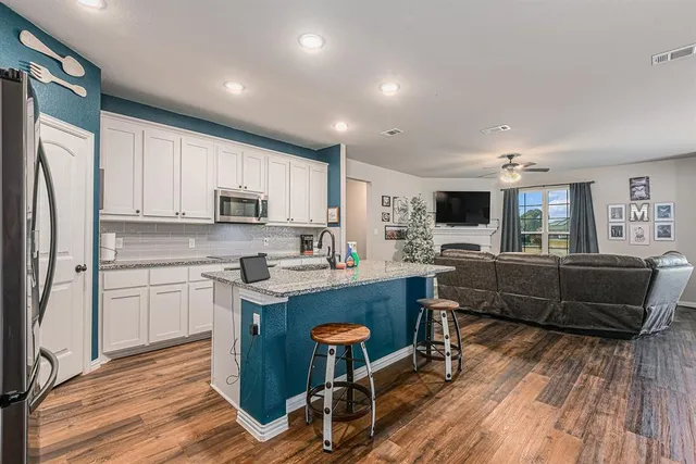 a kitchen with kitchen island granite countertop wooden floors and white stainless steel appliances