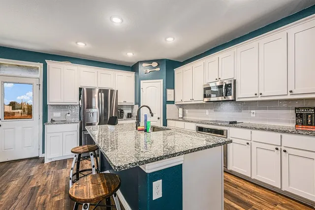 a kitchen with stainless steel appliances granite countertop a sink refrigerator and microwave