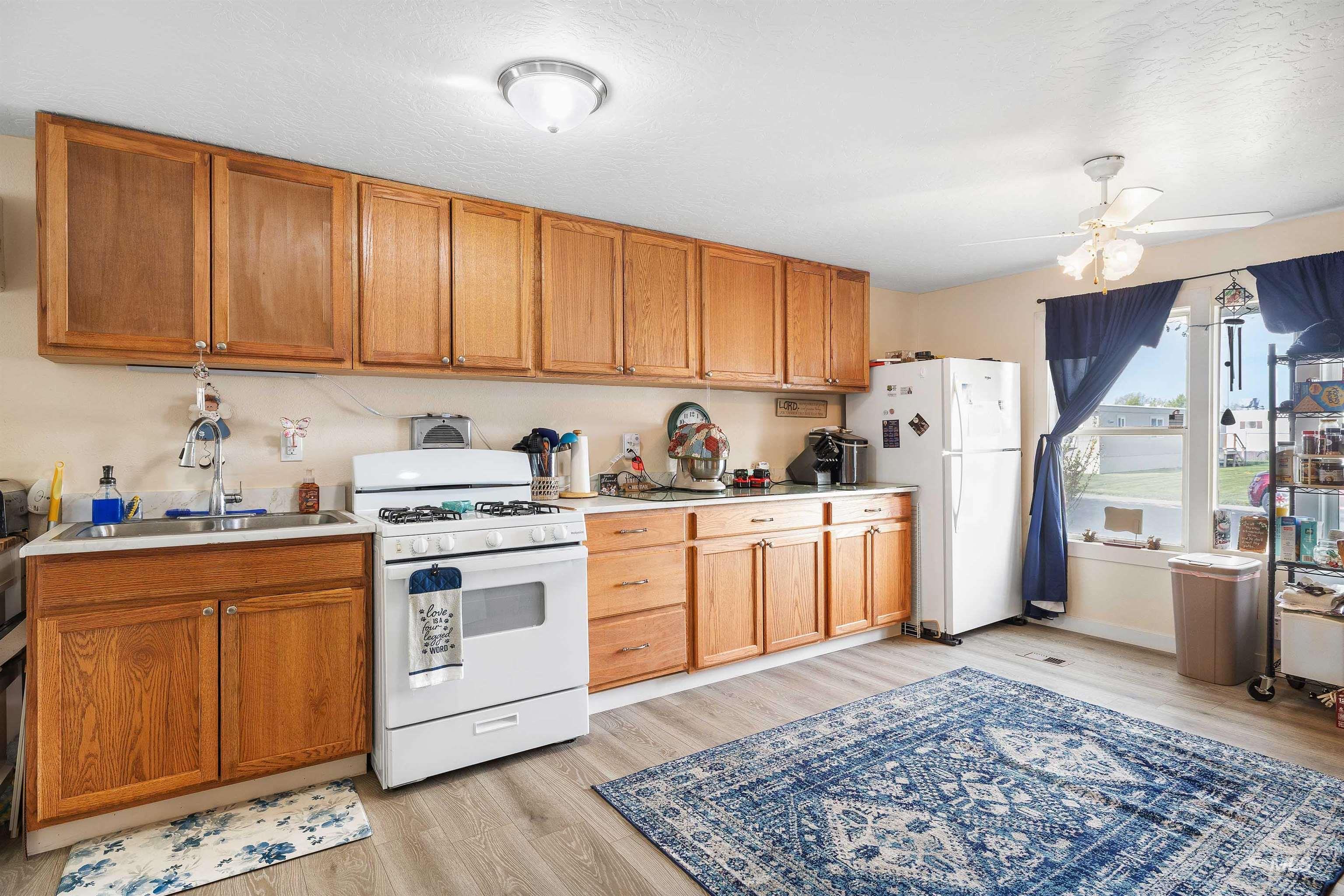 198 South Hills Road, Unit 116 Twin Falls, ID 83301 - Photo 5 of 21 Kitchen featuring light countertops, white appliances, a ceiling fan, wood finish cabinets, and a textured ceiling
