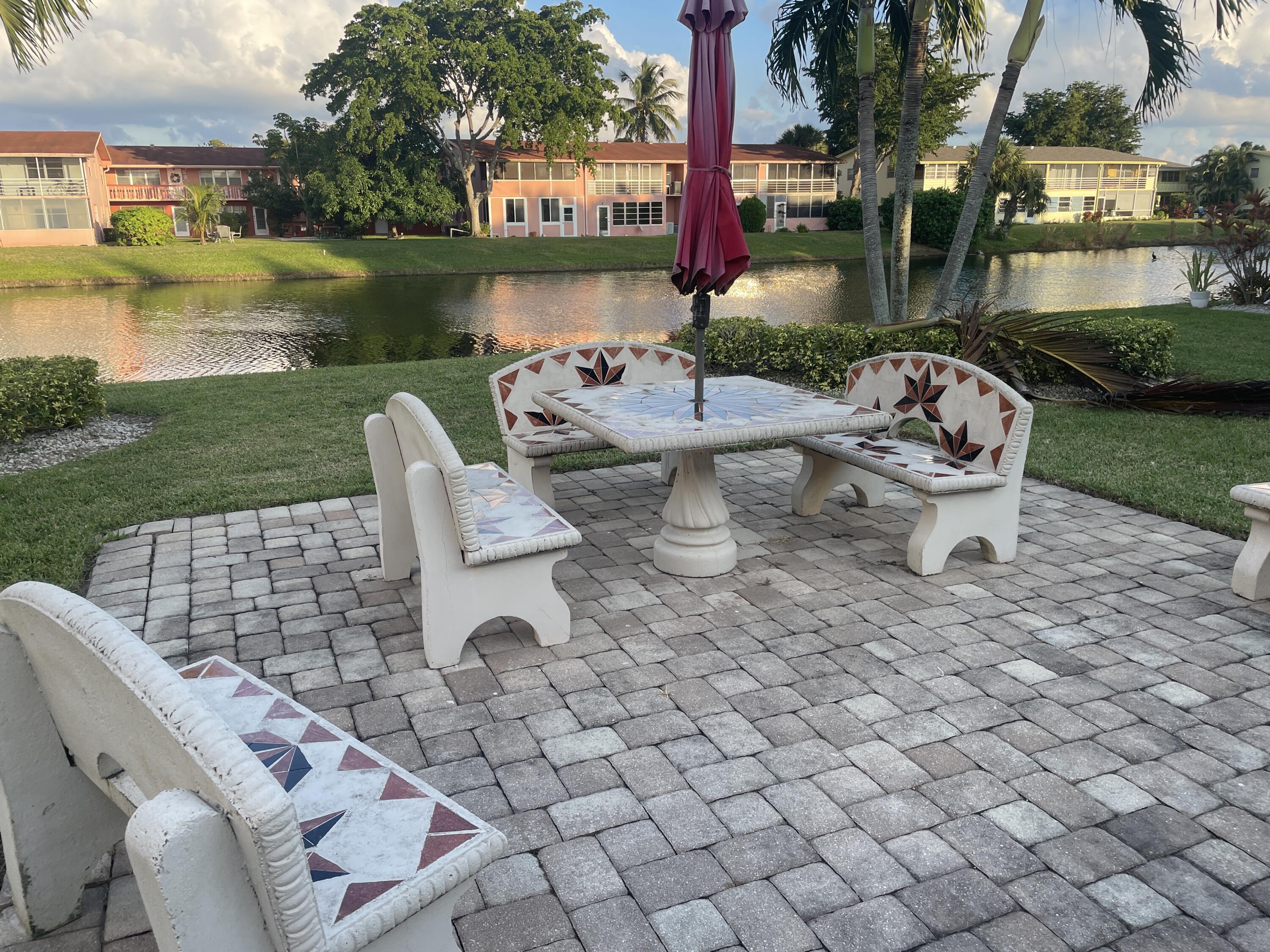 183 Dorchester East, Unit H West Palm Beach, FL 33417 - Photo 16 of 28 a view of a lake with couches chairs and a table
