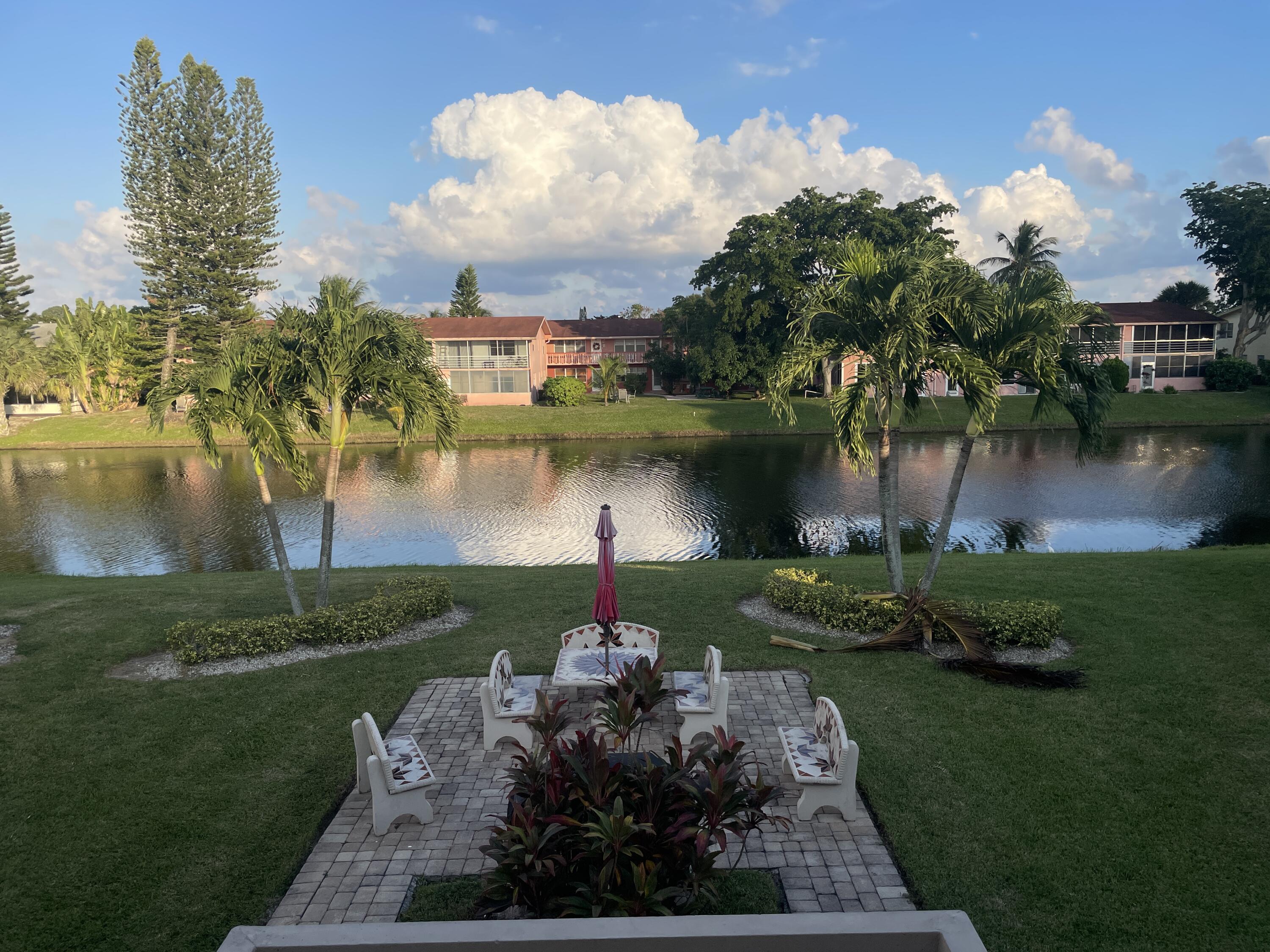 183 Dorchester East, Unit H West Palm Beach, FL 33417 - Photo 18 of 28 a view of a lake with a garden and a houses