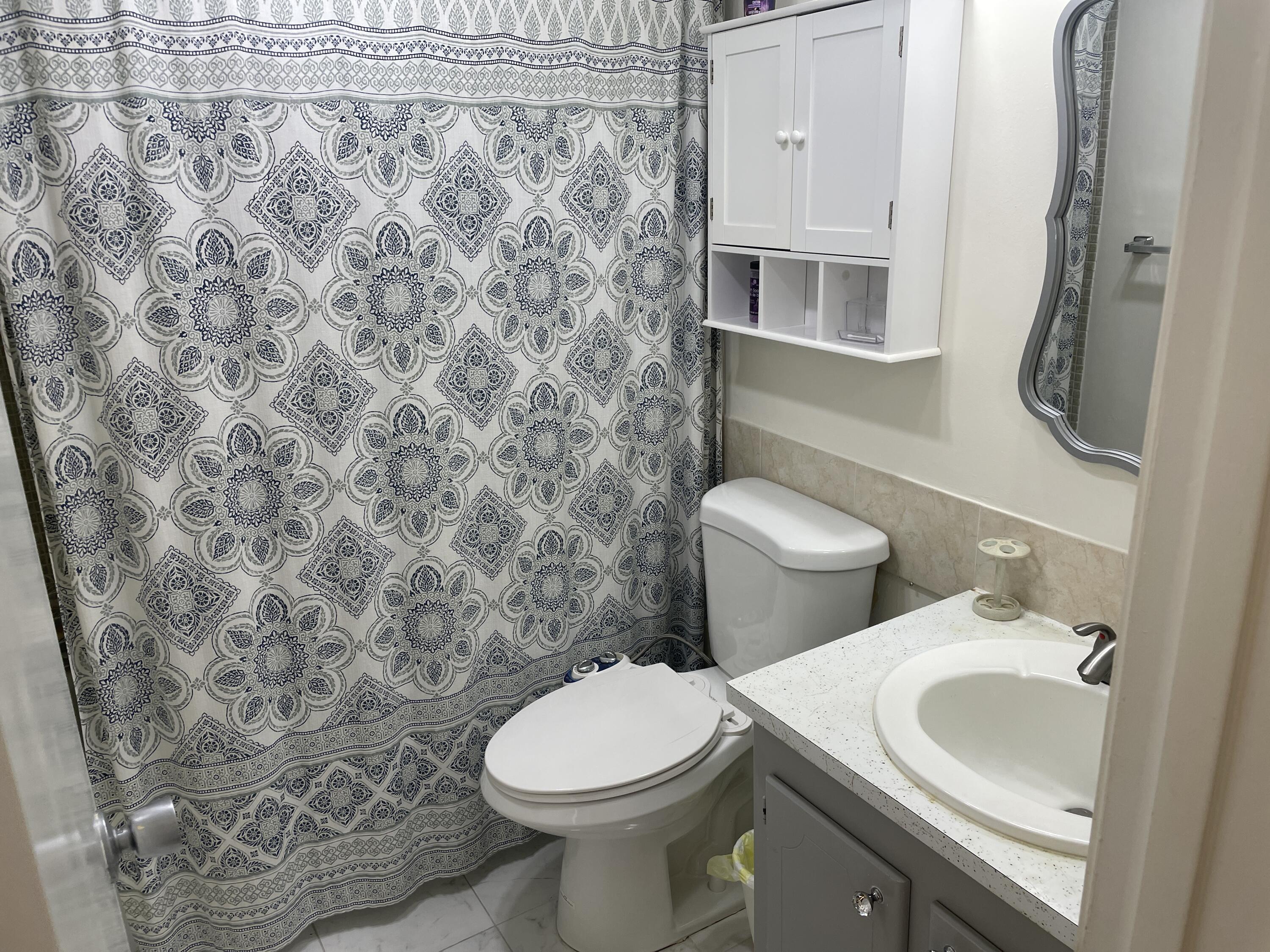 183 Dorchester East, Unit H West Palm Beach, FL 33417 - Photo 5 of 28 a white toilet sitting next to a bathroom sink