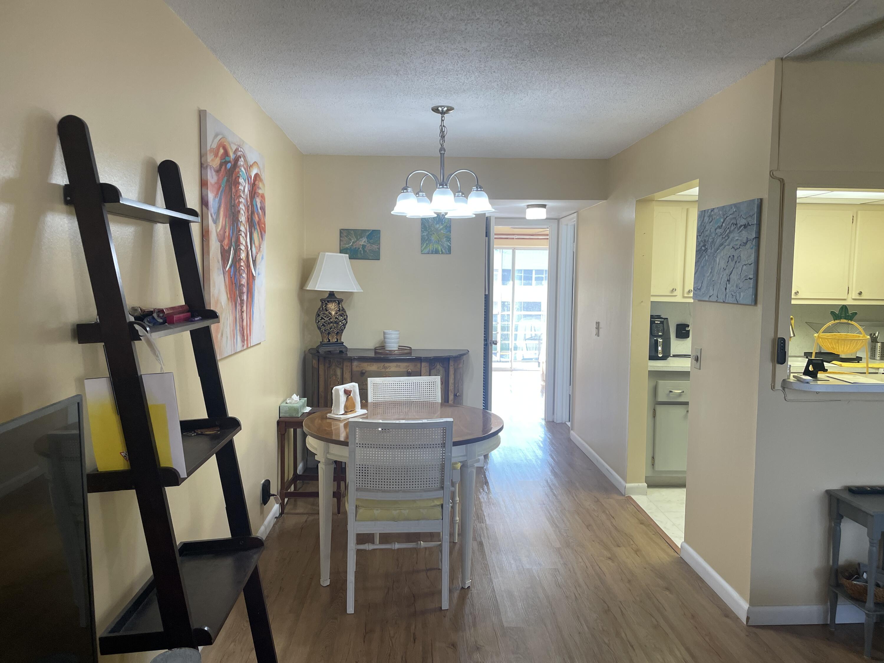 183 Dorchester East, Unit H West Palm Beach, FL 33417 - Photo 7 of 28 a view of a dining room with furniture and a chandelier