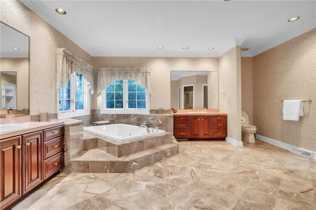 a spacious bathroom with a tub sink and mirror