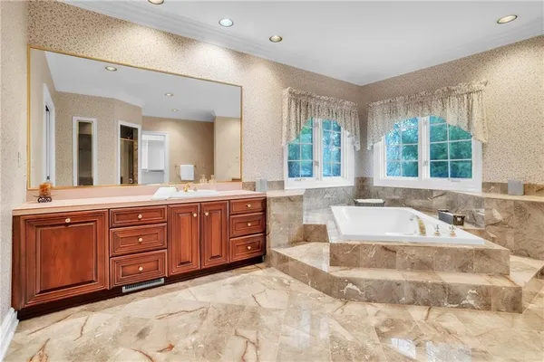 a spacious bathroom with a tub sink and mirror