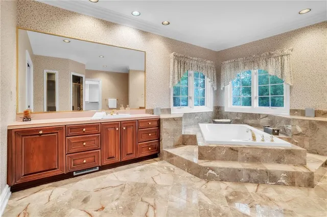 a spacious bathroom with a tub sink and mirror