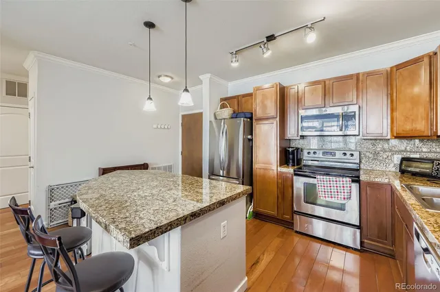 a kitchen with stainless steel appliances granite countertop a kitchen island hardwood floor and a sink