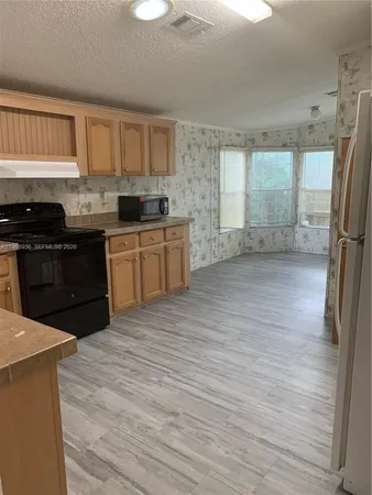 a large kitchen with a stove a sink dishwasher a refrigerator and cabinets with wooden floor
