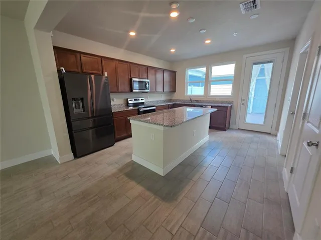 a large kitchen with stainless steel appliances granite countertop a large counter top and wooden floors