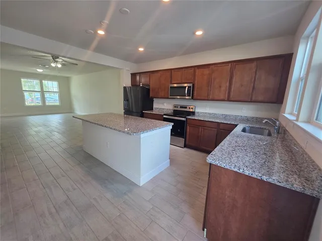 a large kitchen with stainless steel appliances granite countertop a stove a sink and a microwave