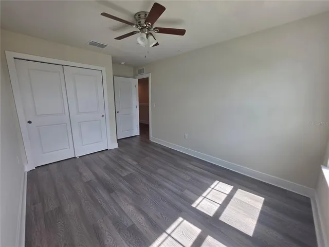 a view of empty room with wooden floor and fan