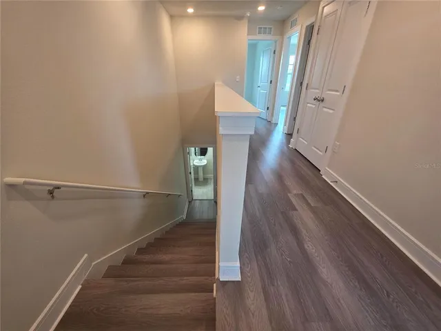 a view of a hallway with wooden floor and staircase