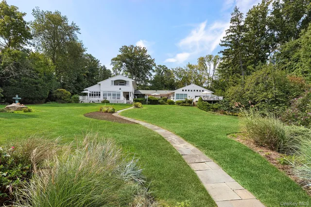 a front view of a house with garden and trees