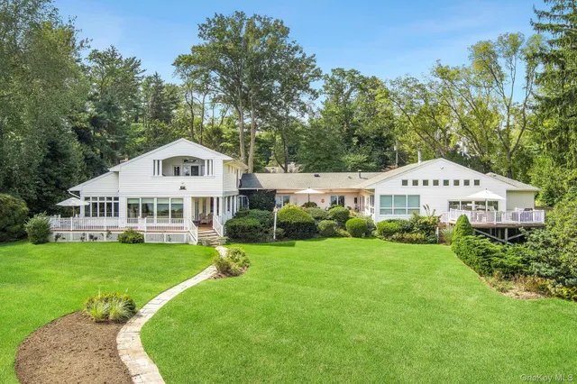 a white house with a big yard and large trees