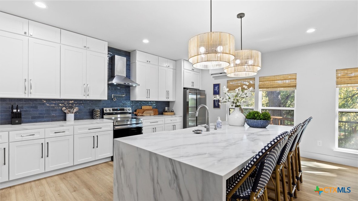 6786 River Road New Braunfels, TX 78132 - Photo 7 of 38 a kitchen with stainless steel appliances kitchen island granite countertop a stove a sink a refrigerator a center island a dining table and chairs with wooden floor