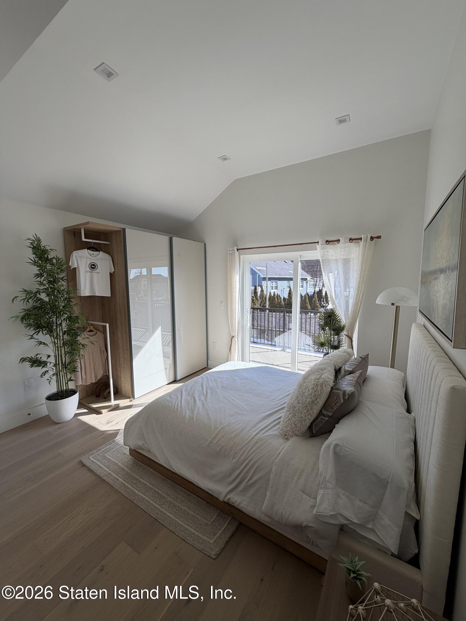 1239 Forest Hill Road, Unit 7 Staten Island, NY 10314 - Photo 11 of 14 a bedroom with a bed a mirror and potted plant