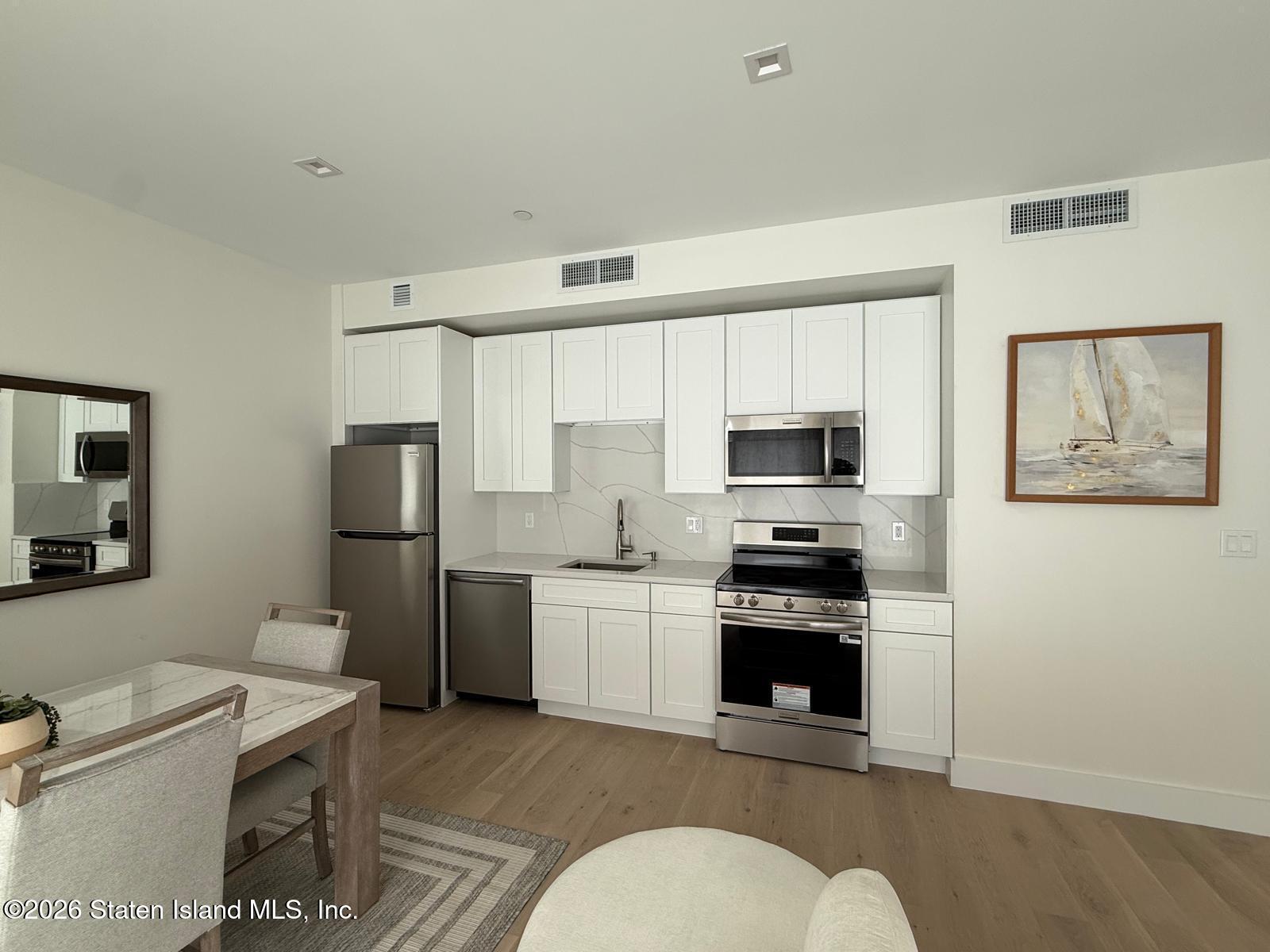 1239 Forest Hill Road, Unit 7 Staten Island, NY 10314 - Photo 5 of 14 a kitchen with stainless steel appliances a stove a refrigerator and a stove top oven