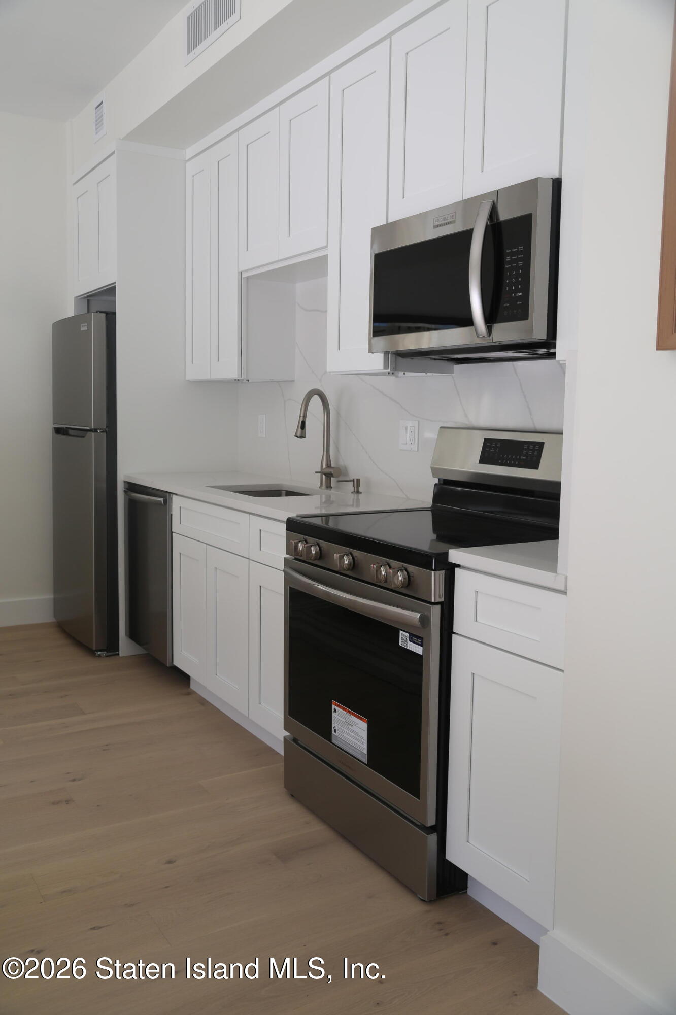 1239 Forest Hill Road, Unit 7 Staten Island, NY 10314 - Photo 6 of 14 a kitchen with stainless steel appliances a stove a microwave a sink and cabinets