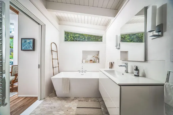 a bathroom with a white tub sink and mirror