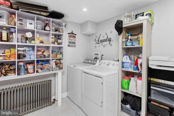a utility room with fridge dryer and baby on a shelf