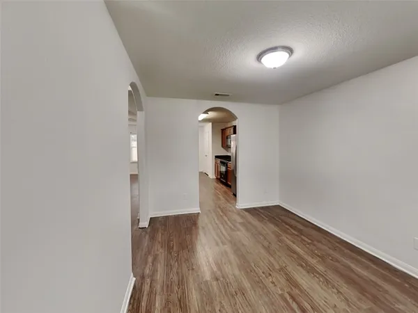 an empty room with wooden floor chandelier fan and windows