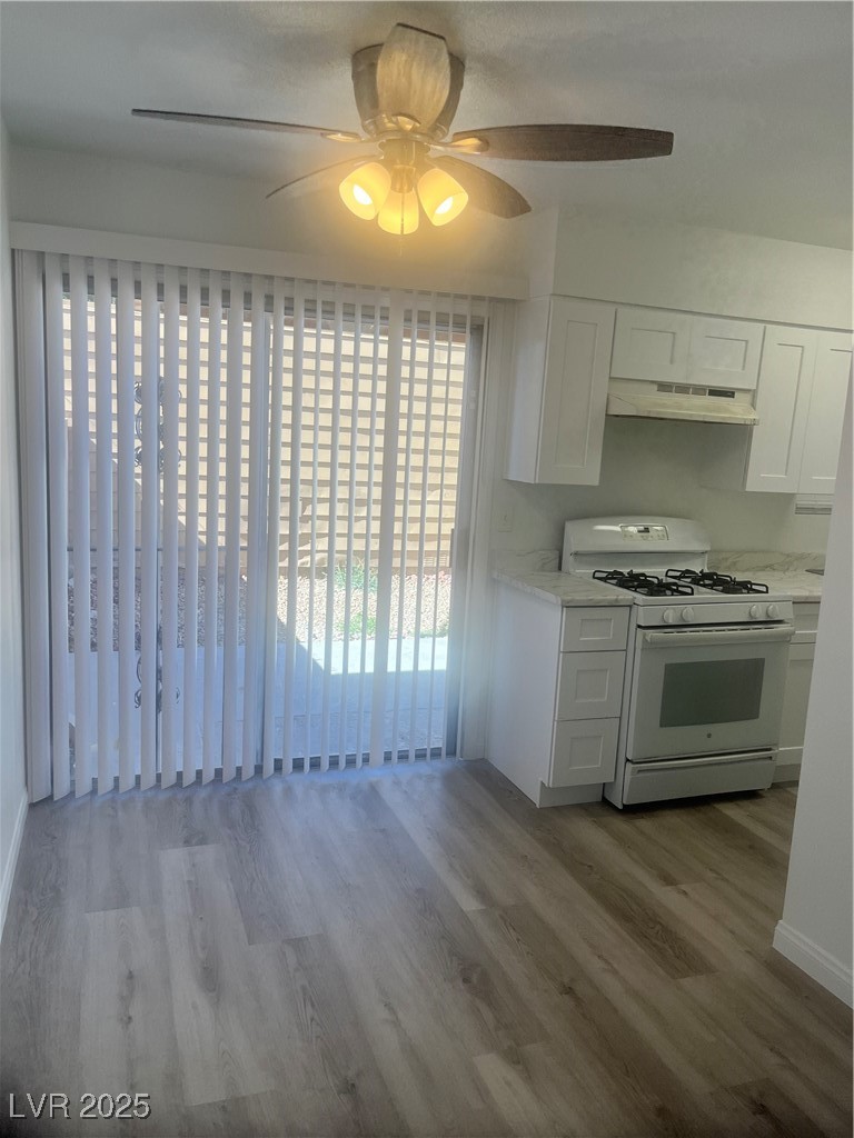 592 Sea Shell Lane Las Vegas, NV 89110 - Photo 5 of 24 Kitchen featuring stove, ceiling fan, white cabinetry, light wood-style flooring, and exhaust hood