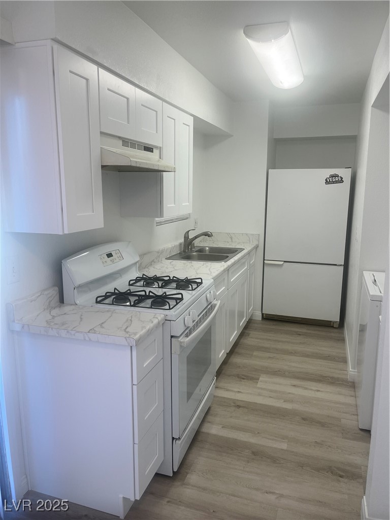 592 Sea Shell Lane Las Vegas, NV 89110 - Photo 6 of 24 Kitchen with white appliances, light countertops, white cabinetry, light wood-style floors, and extractor fan