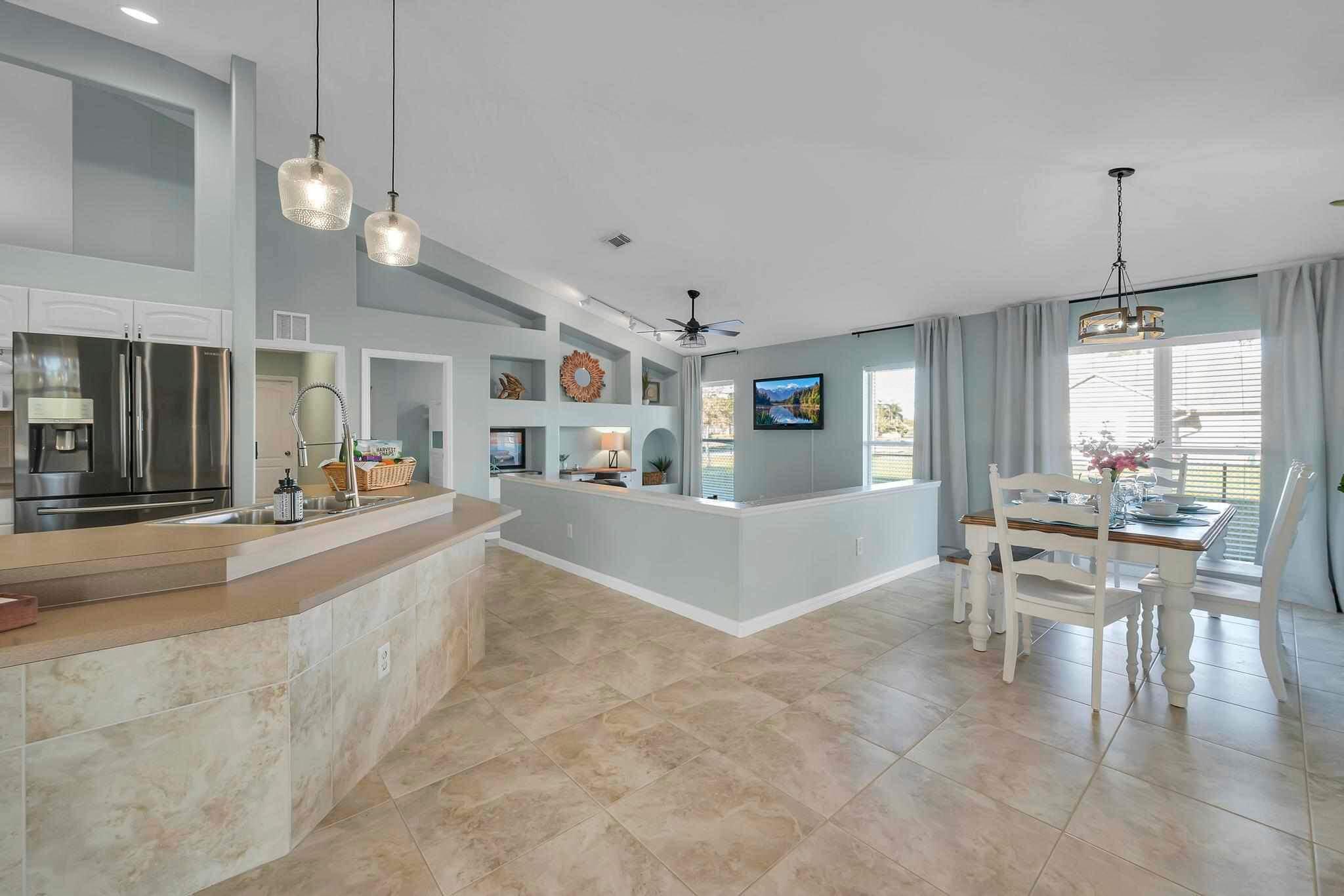 5464 Northwest Milner Drive Port St. Lucie, FL 34983 - Photo 11 of 49 a large white kitchen with lots of counter space and chandelier