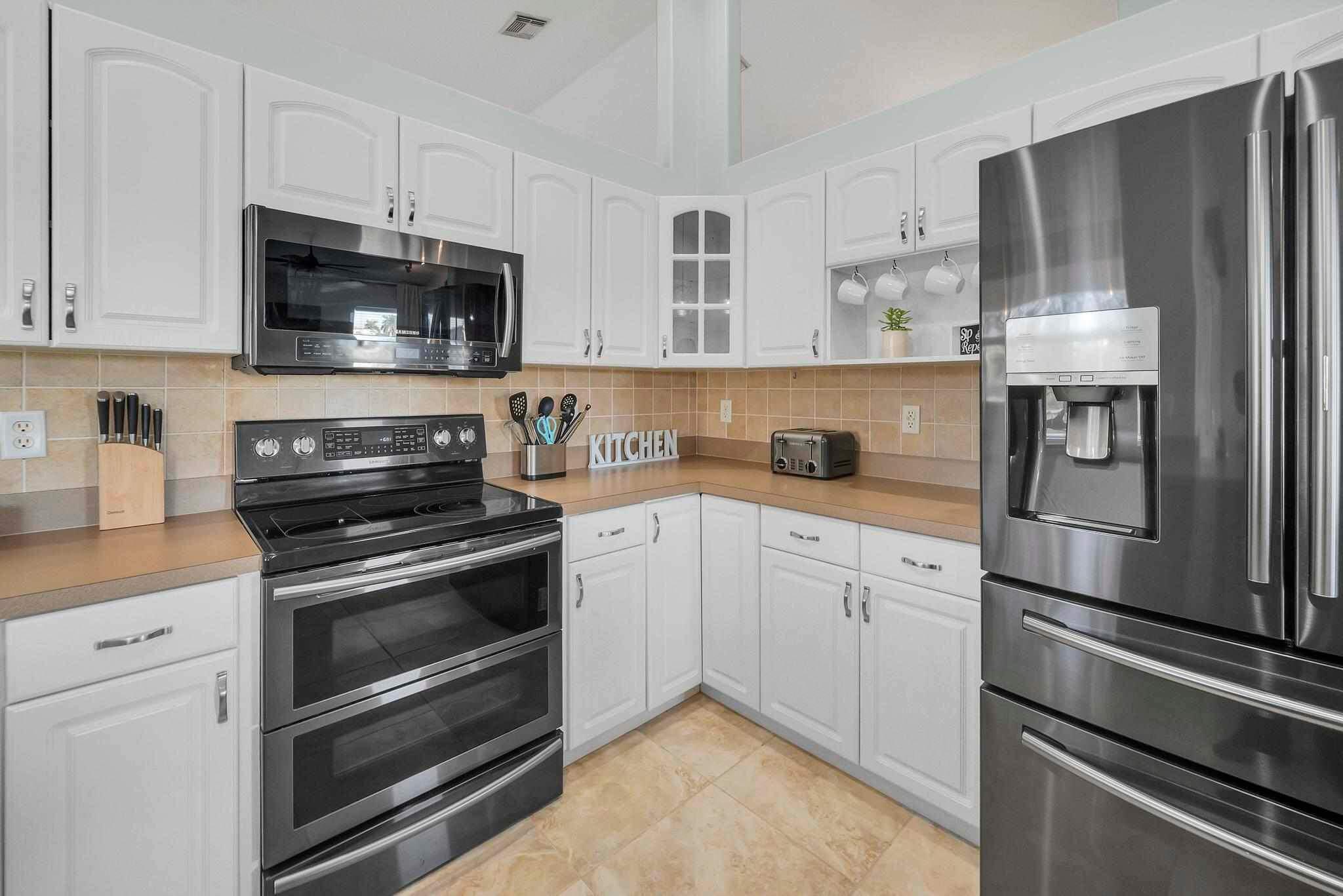 5464 Northwest Milner Drive Port St. Lucie, FL 34983 - Photo 15 of 49 a kitchen with stainless steel appliances white cabinets white stove a sink and a refrigerator
