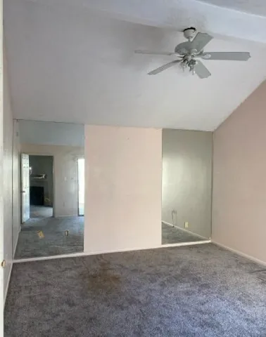 an empty room with closet and a chandelier fan