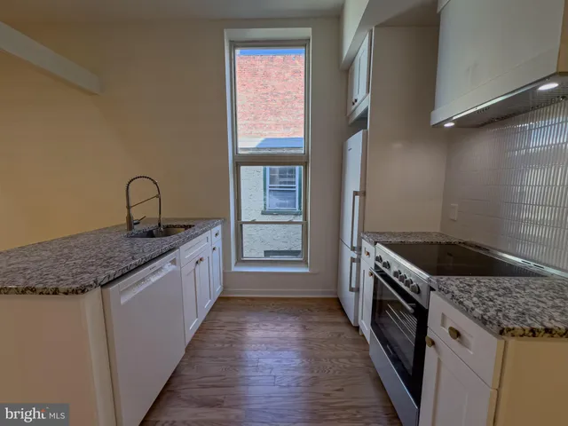 a kitchen with a granite countertop sink and cabinets