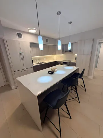 a large white kitchen with a large kitchen island a stove and a sink