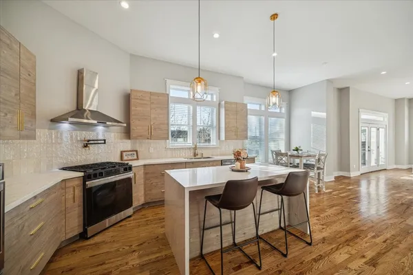 a kitchen with stainless steel appliances granite countertop a sink a stove a refrigerator and island with wooden floor