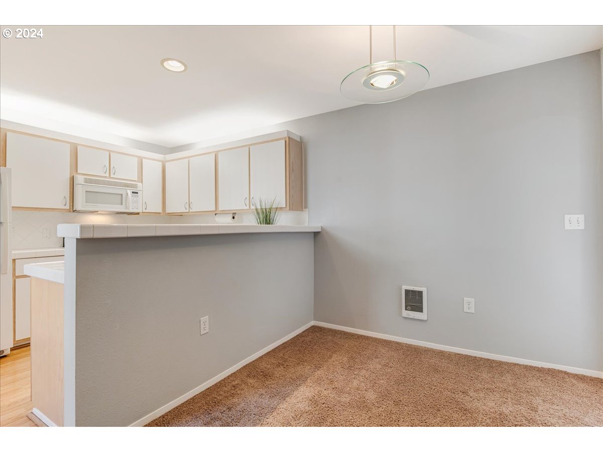 5225 Jean Road, Unit 313 Lake Oswego, OR 97035 - Photo 8 of 32 a kitchen with kitchen island a sink dishwasher a stove and white countertops with wooden floor