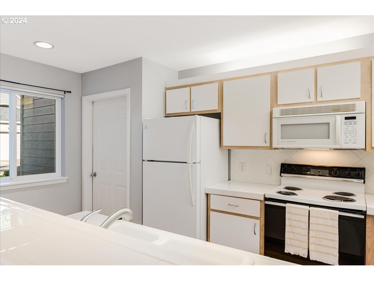 5225 Jean Road, Unit 313 Lake Oswego, OR 97035 - Photo 10 of 32 a kitchen with a refrigerator stove and white cabinets