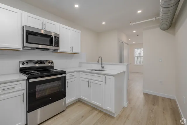 a kitchen with stainless steel appliances granite countertop a sink a stove a microwave and wooden cabinets