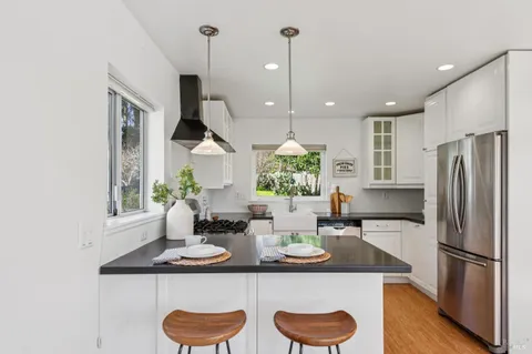 a kitchen with stainless steel appliances granite countertop a sink a stove a refrigerator and island with wooden floor