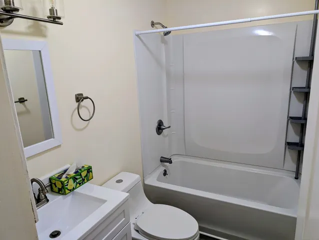 a bathroom with a toilet sink vanity tub and shower