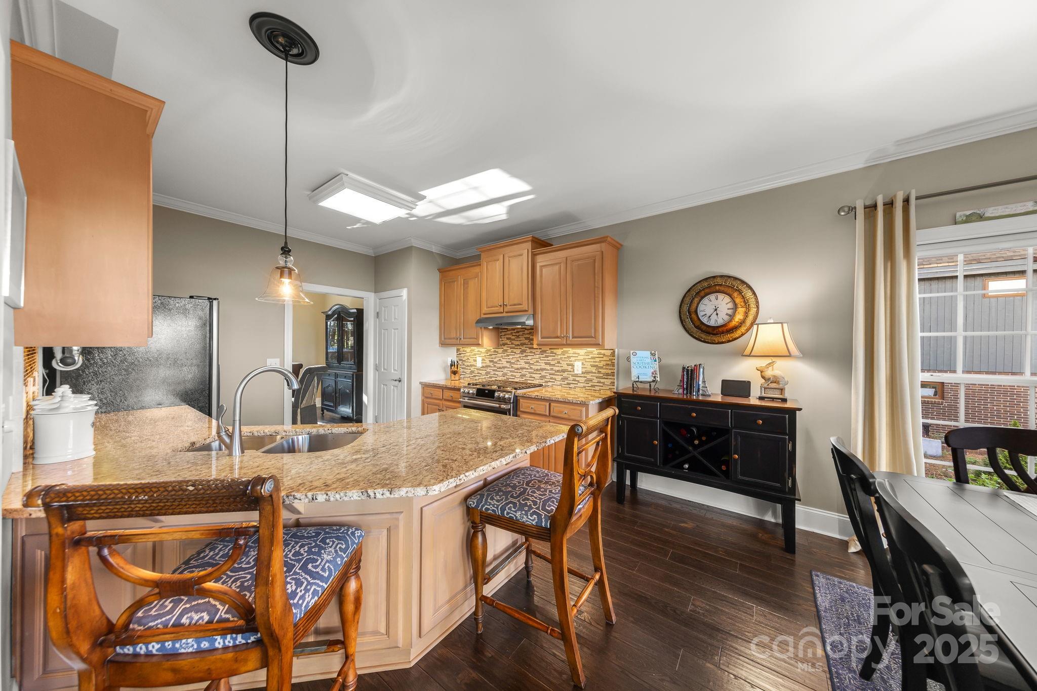 796 Lake Mist Drive Stanley, NC 28164 - Photo 16 of 43 a kitchen with granite countertop a stove a sink and a dining table with chairs